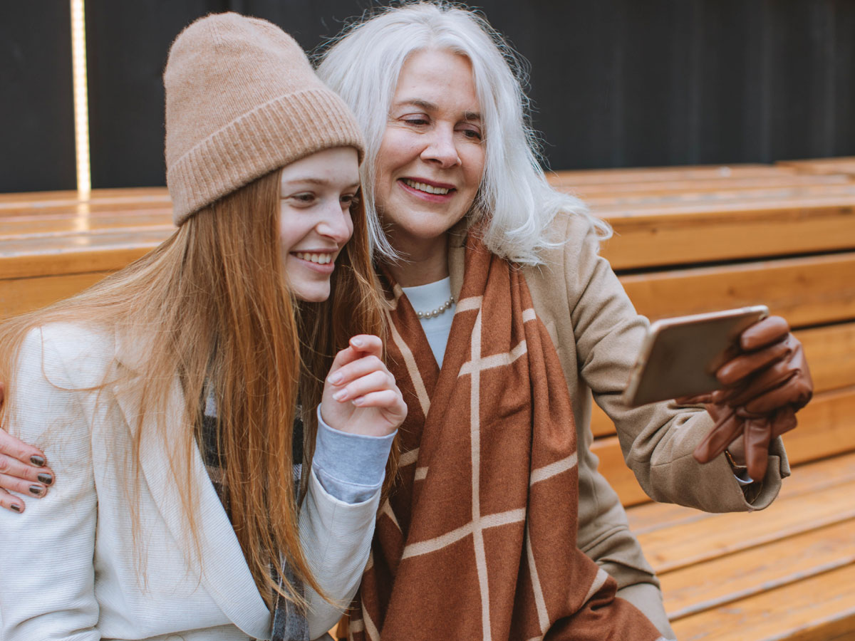 Mother and daughter sitting on park bench
